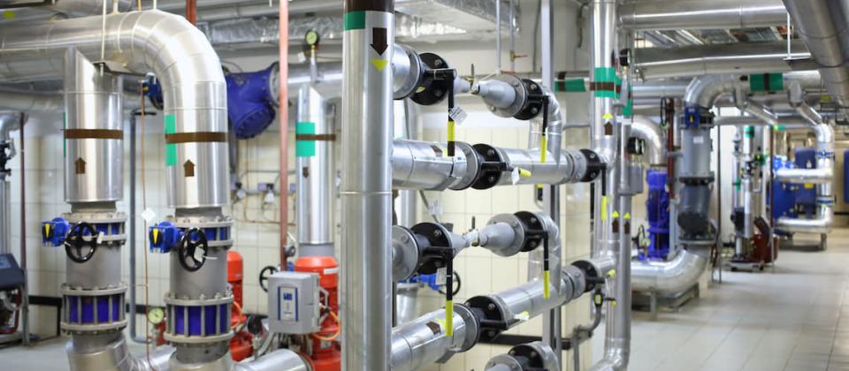 Industrial piping and pumps in a plant room — industrial equipment market